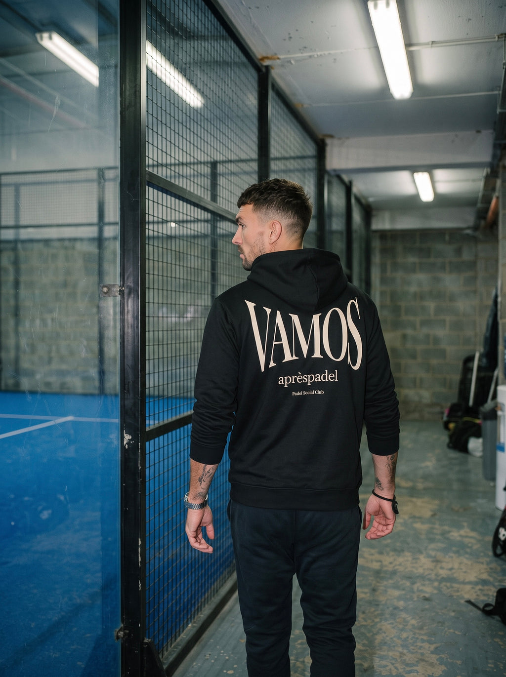 AP Club Vamos Hoodie in black photographed at a padel court