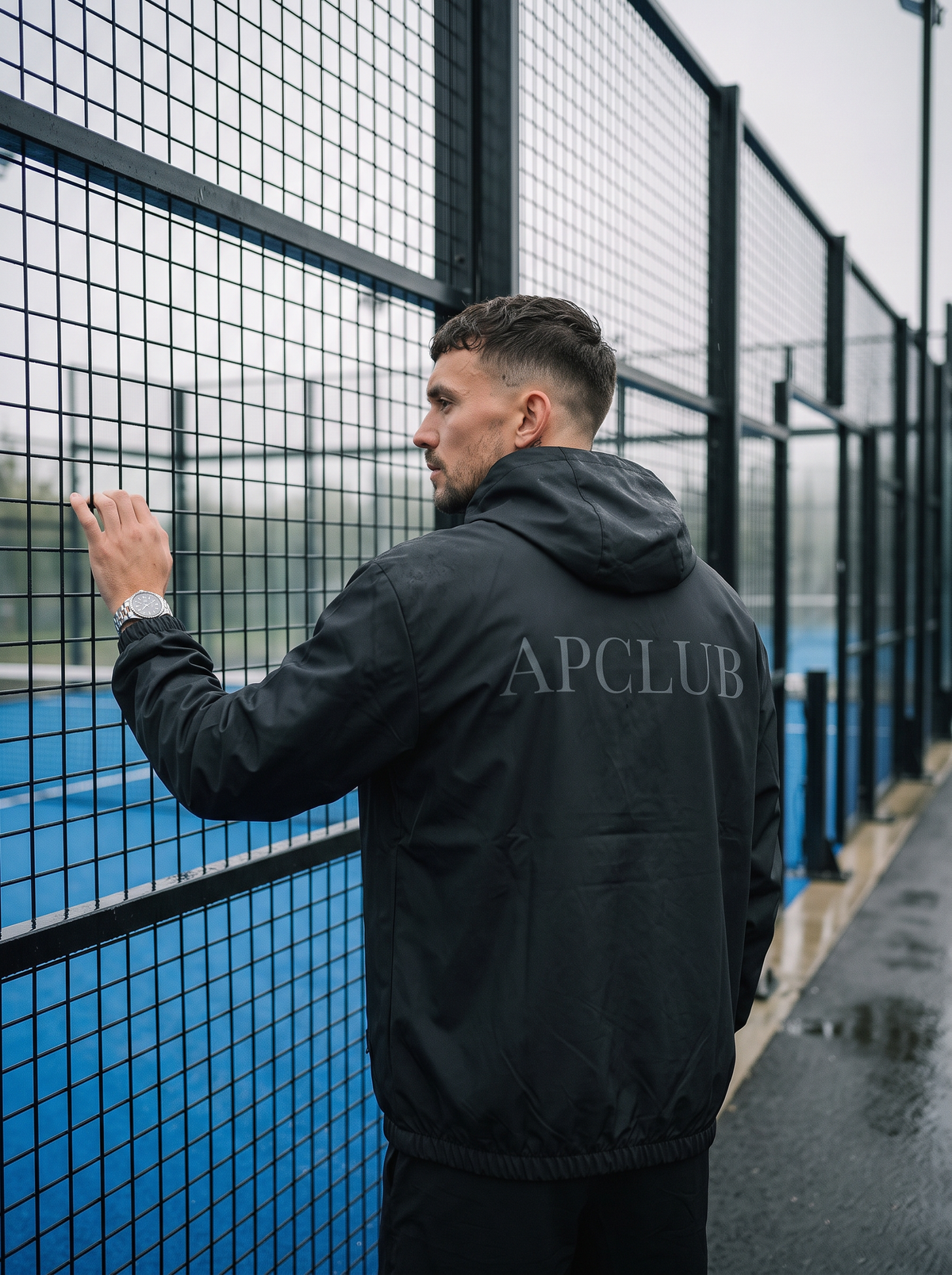 AP Club lightweight black padel shell jacket beside the court