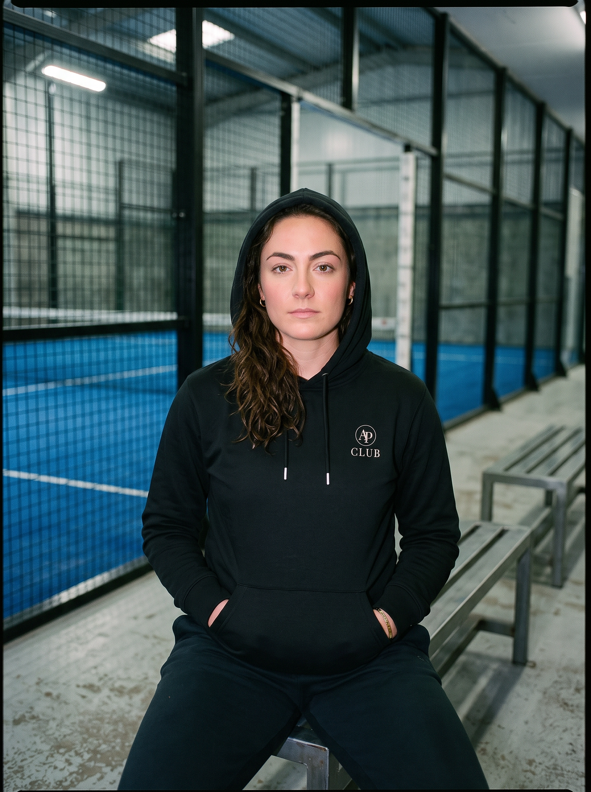 AP Club Vamos Hoodie with VAMOS back print beside a padel court