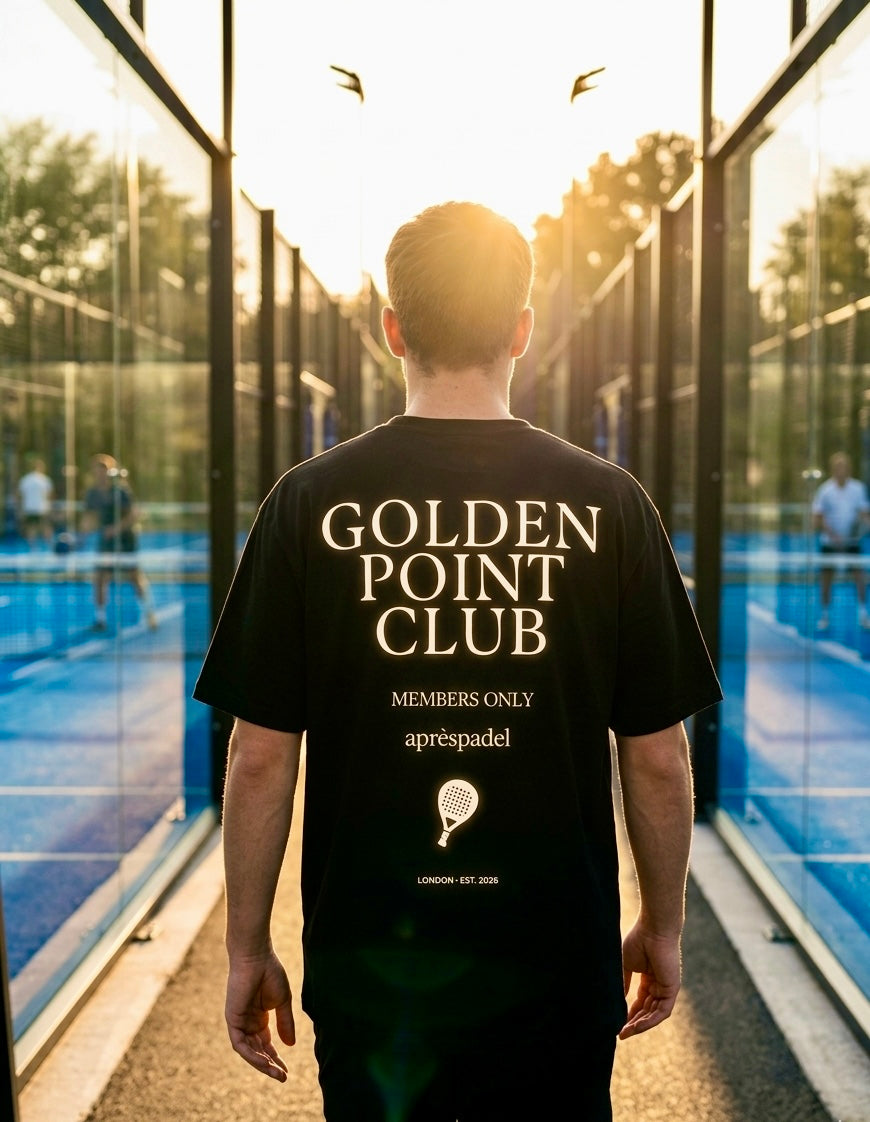 Padel player wearing a blackAP Club  'Golden Point Club' t-shirt in an outdoor padel court setting with glass walls.