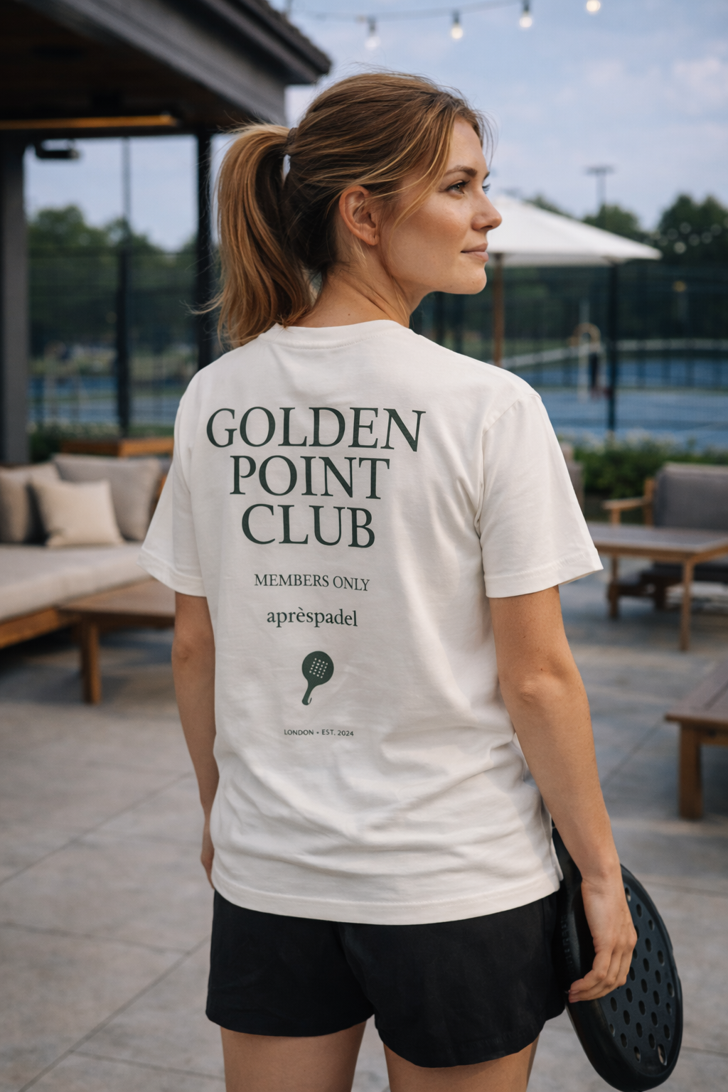 Woman wearing a 'Golden Point Club' AP Club t-shirt outdoors.